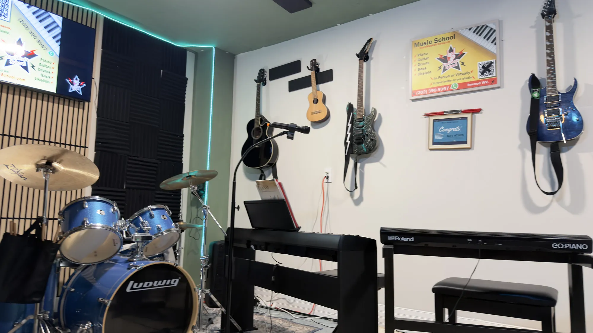 The Stars Music School studio lit in purple, with drums, piano and guitars